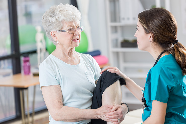 Lady holding her knee talking to healthcare professional